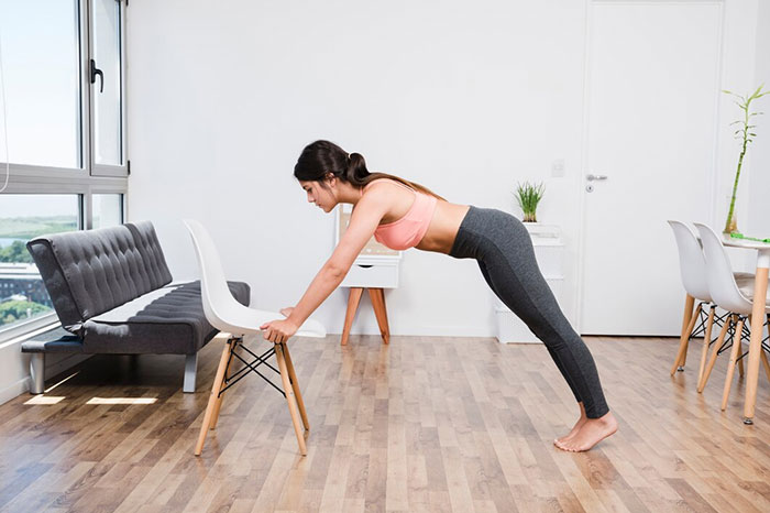 Person using a chair for a unique exercise pose, demonstrating a creative body life hack.