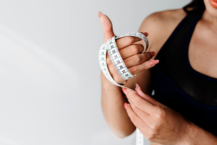 Person holding a measuring tape, illustrating crazy body life hacks for fitness goals.