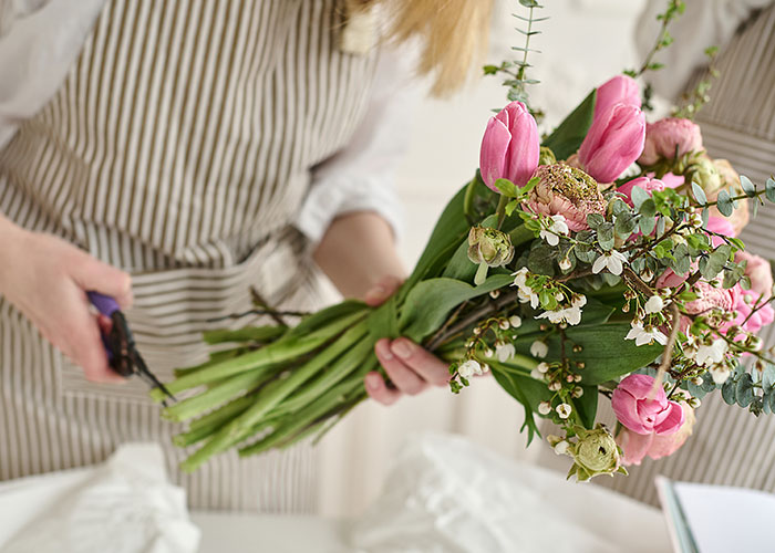 Florist arranging a bouquet, wearing a striped apron, emphasizing creativity and handcraft in relationship-themed stories.