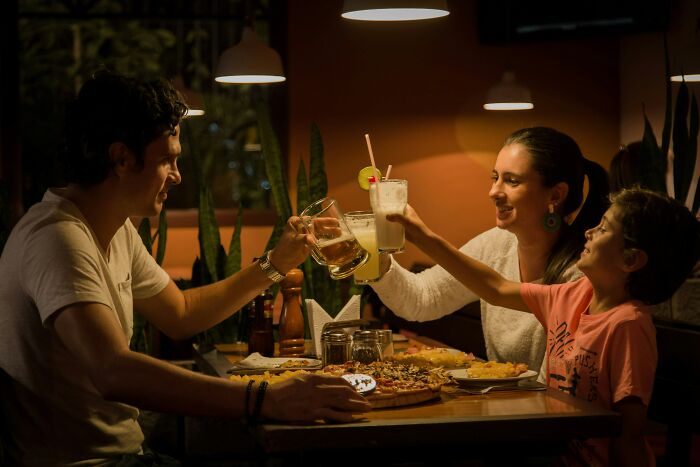 Family dining, toasting drinks at a restaurant, capturing secrets and love in a joyful moment.