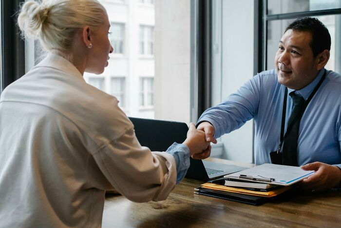 Man and woman shaking hands at a desk, symbolizing secrets kept from loved ones.