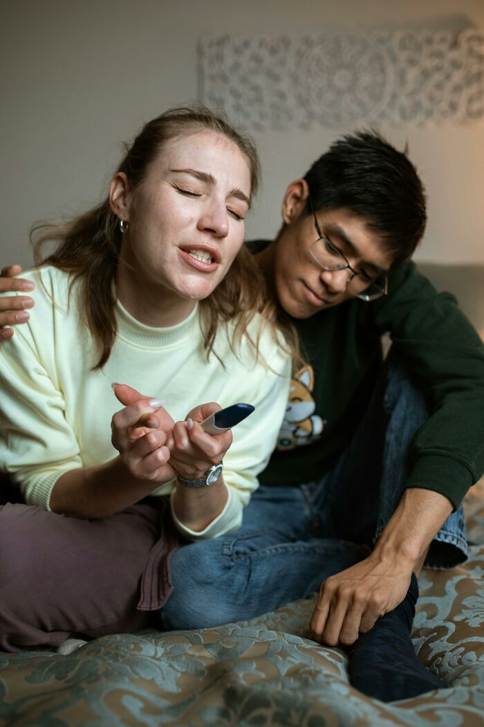 Couple sitting on a bed, sharing an emotional moment, highlighting secrets kept from loved ones.