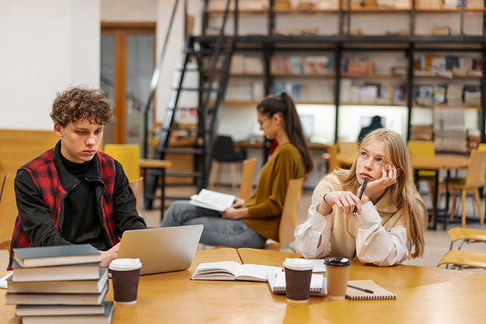 Teenagers in a library setting; one appears deep in thought, highlighting ADHD symptoms in a 17-year-old.