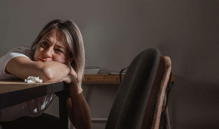 A worried mom at a table, contemplating struggles with her 17-year-old possibly indicating ADHD symptoms.