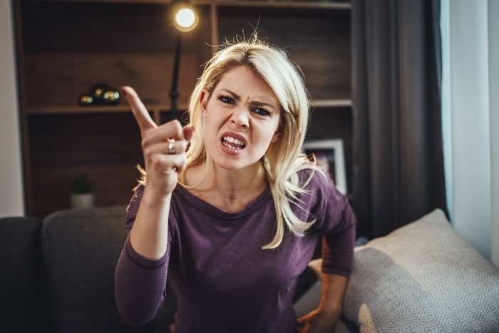 A woman with blonde hair looks upset, pointing her finger in a domestic setting, related to daughter-phone-mom-tracker.