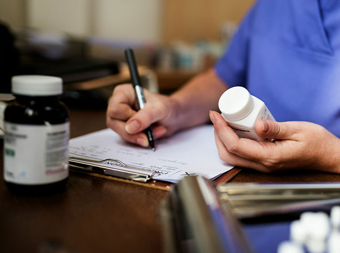 Healthcare worker reviewing medication and insurance claims paperwork.