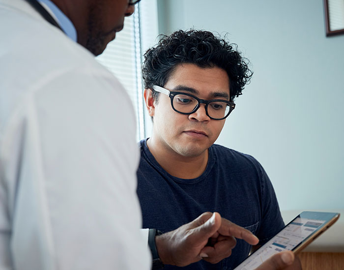 Man consulting with a professional about denied insurance claims, using a tablet for reference.