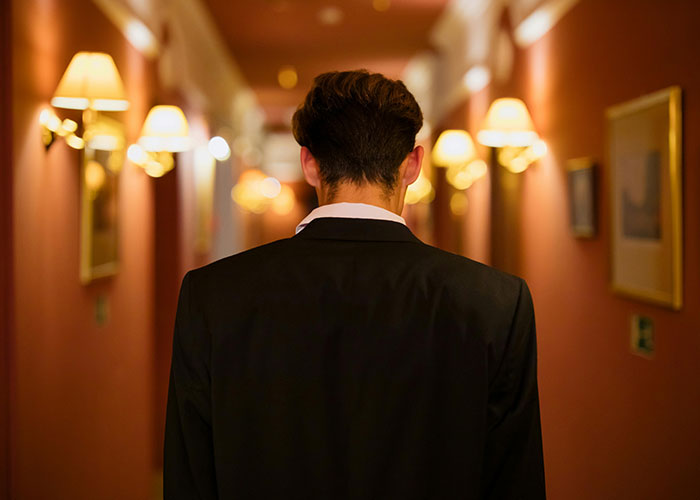 Person in a suit walks down a dimly lit hallway, symbolizing CEO management struggles.