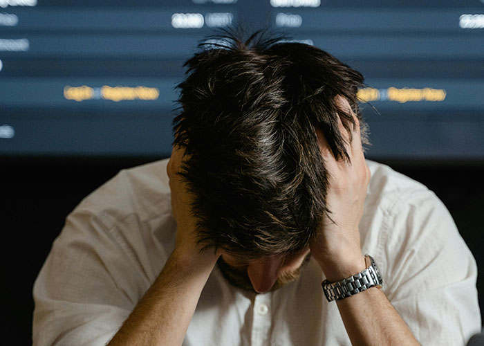 Frustrated man in white shirt with head in hands, illustrating CEO management struggles.