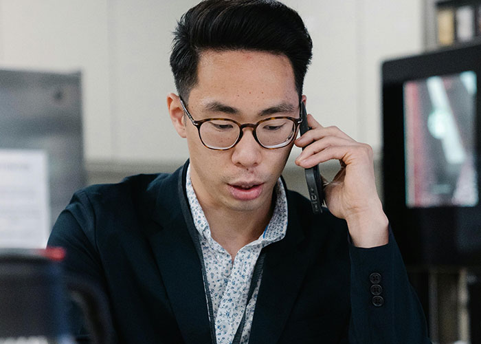 "Man in glasses on phone, illustrating CEO management challenges."