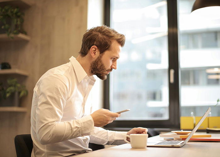 Businessman in white shirt focused on laptop, illustrating CEO management challenges.