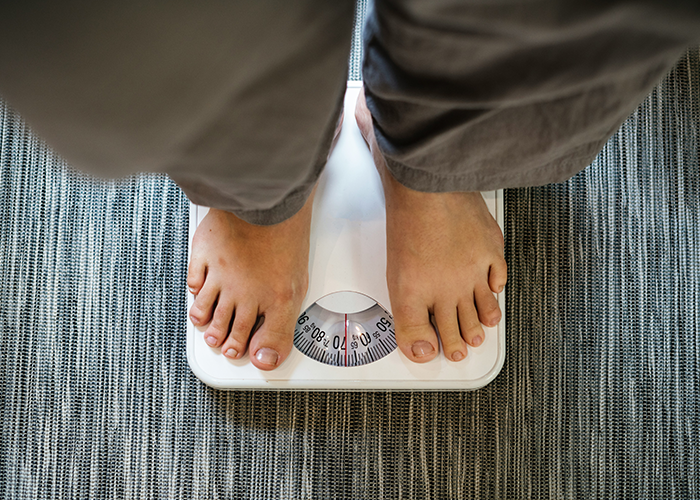 Person standing on a scale, highlighting issues related to fat-shaming and body image perception.