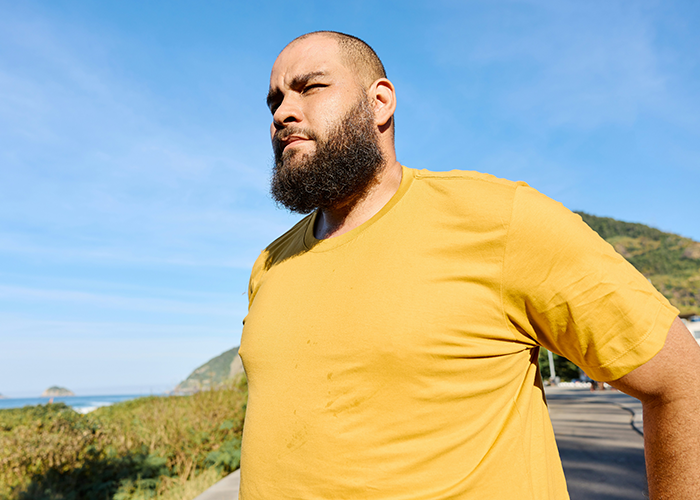 Man in a yellow shirt standing outdoors, embodying confidence despite fat-shaming issues.