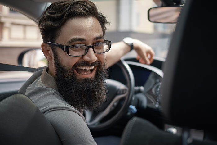 Man in car smiling, possibly planning a fiance house prank.