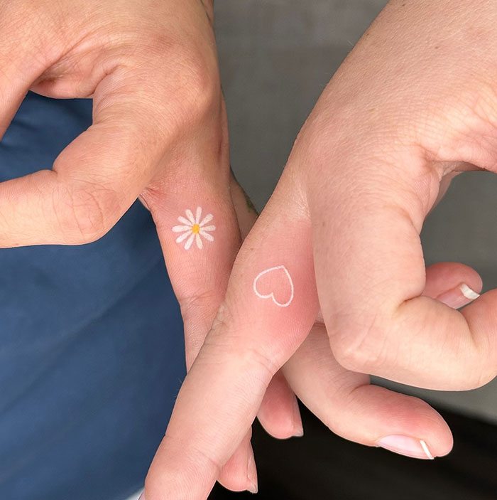 Minimal finger tattoos with a daisy and heart design.