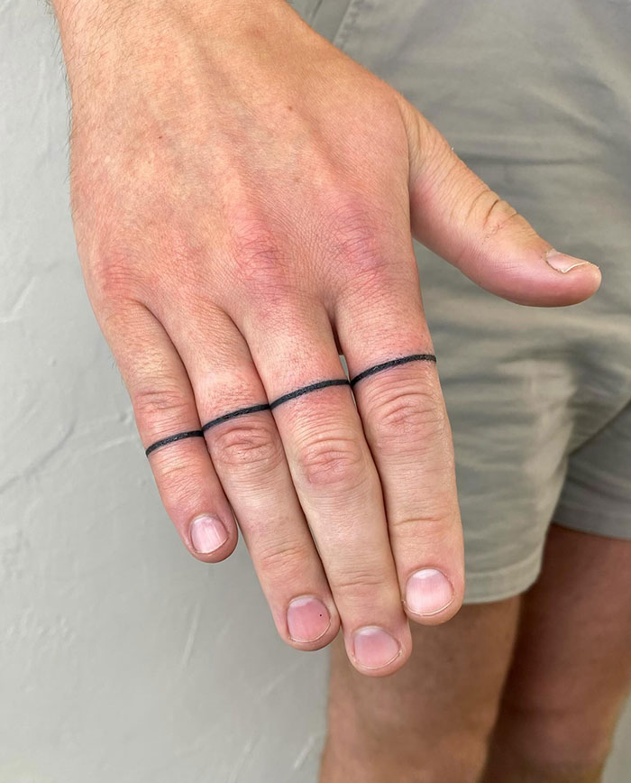 Minimalist line finger tattoos on three fingers with light skin background.