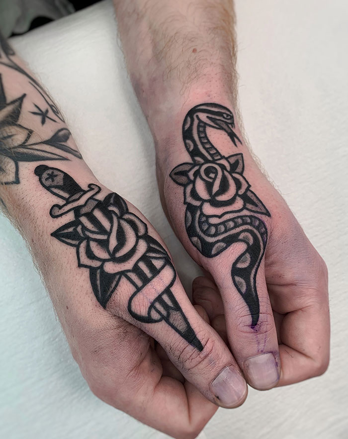 Snake and dagger finger tattoos featuring roses in bold black ink design.