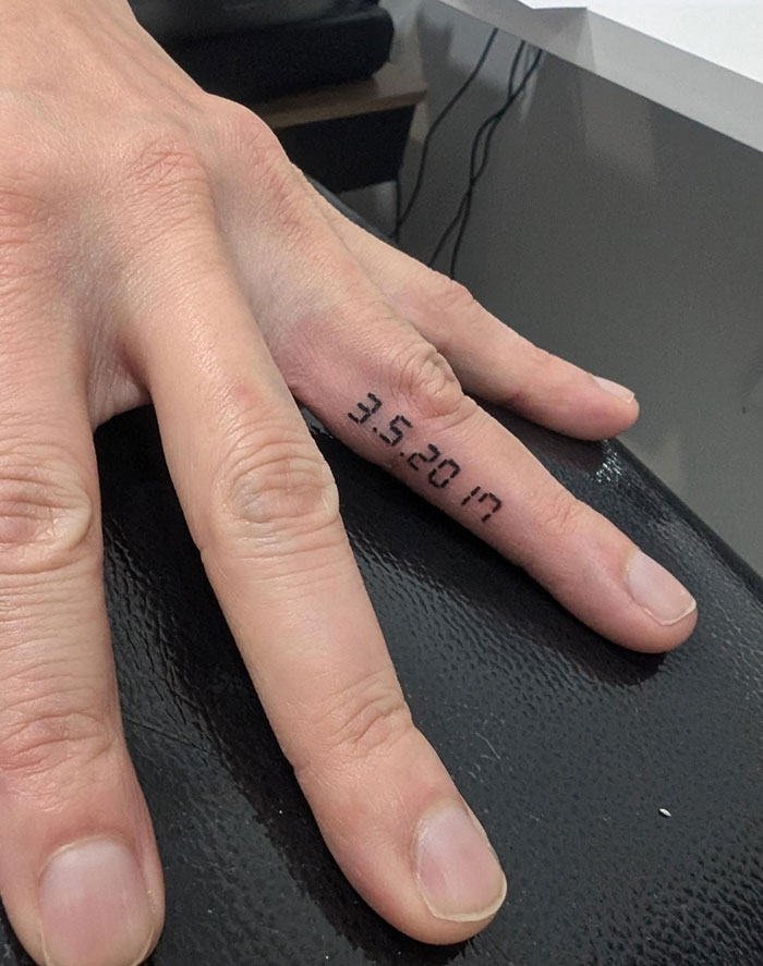 Close-up of finger tattoo with date design on a person's finger.