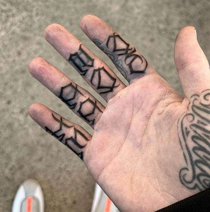 Close-up of intricate finger tattoo designs on a person's hand.