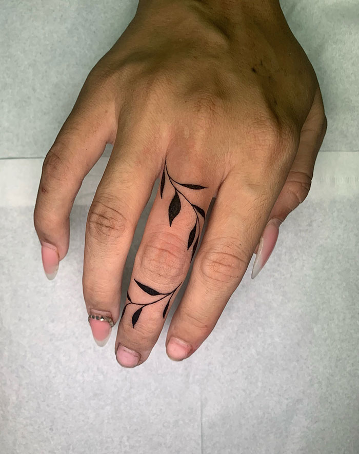 Elegant finger tattoo with leaf design on a hand.