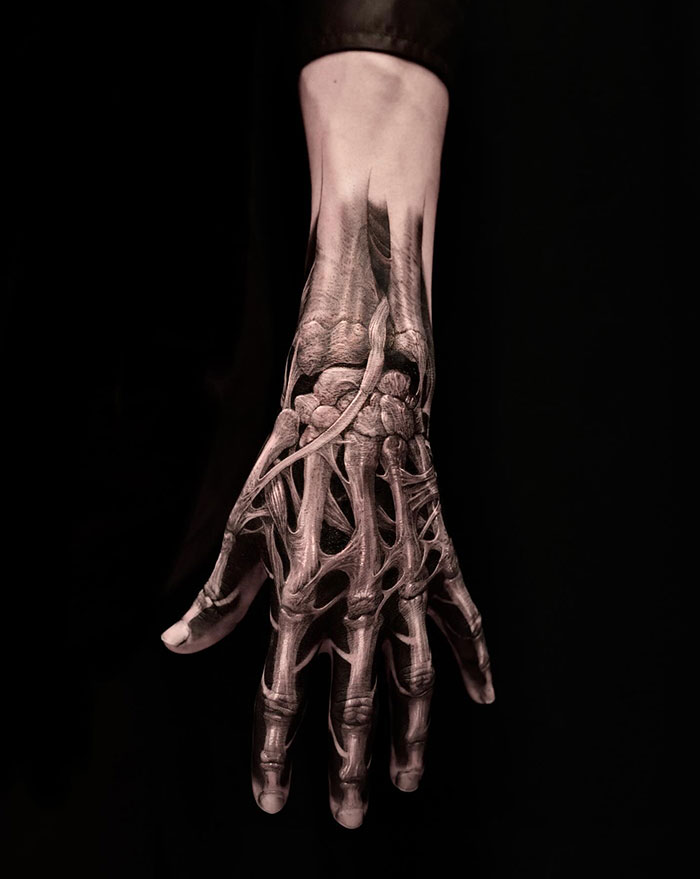 Intricate skeletal finger tattoo design on a hand, showcasing detailed anatomical art.