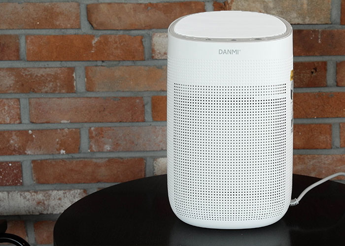 White speaker on a black table in front of a brick wall, showcasing a creative frugal hack.