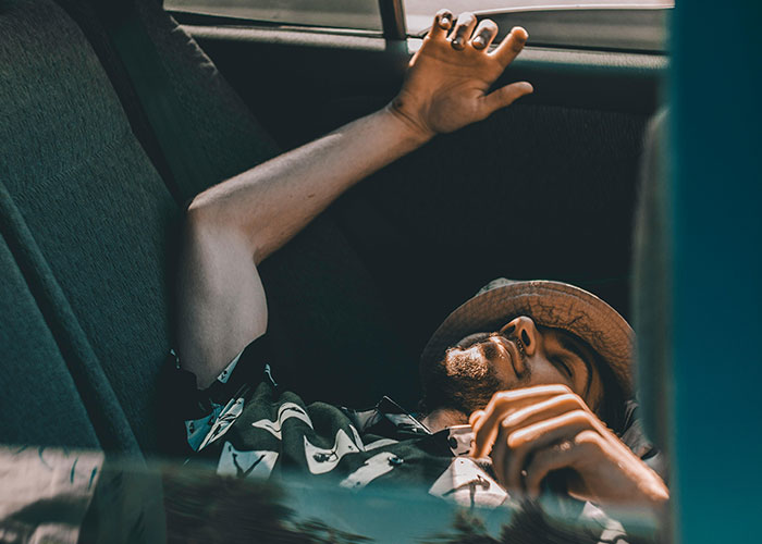 Man relaxing in a car, illustrating creative frugal hacks for saving cash.