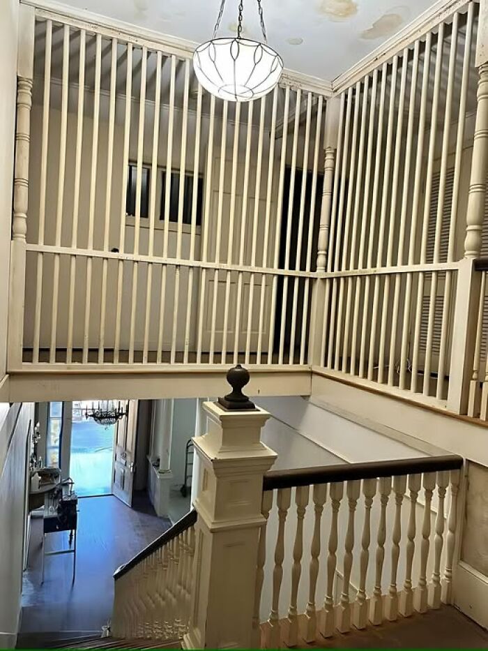 Staircase with awkward design featuring a floor-to-ceiling railing, highlighting a construction fail.