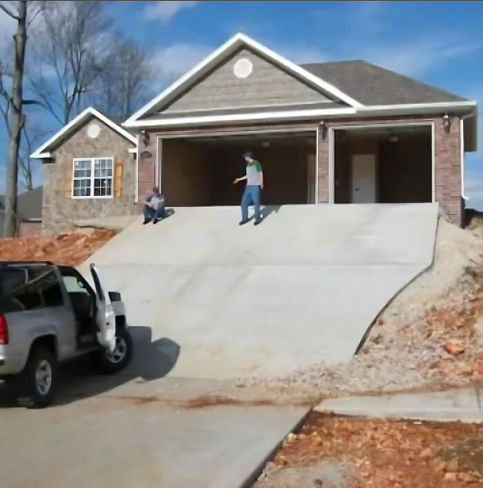 Steep driveway leading to garage with two people on top, illustrating a construction fail.