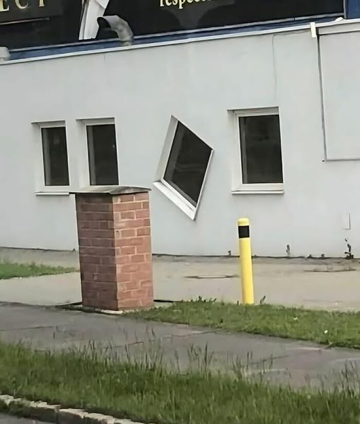 Crooked window in a wall alongside three straight ones, showcasing a funny construction fail.