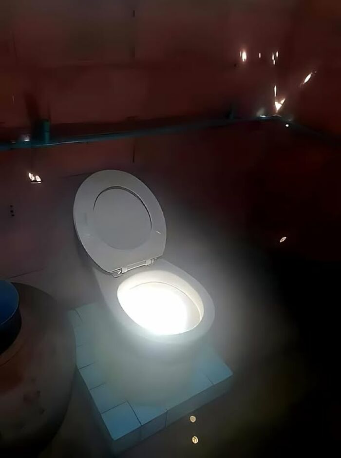 Illuminated toilet seat in a dimly lit room showcasing a humorous construction fail.