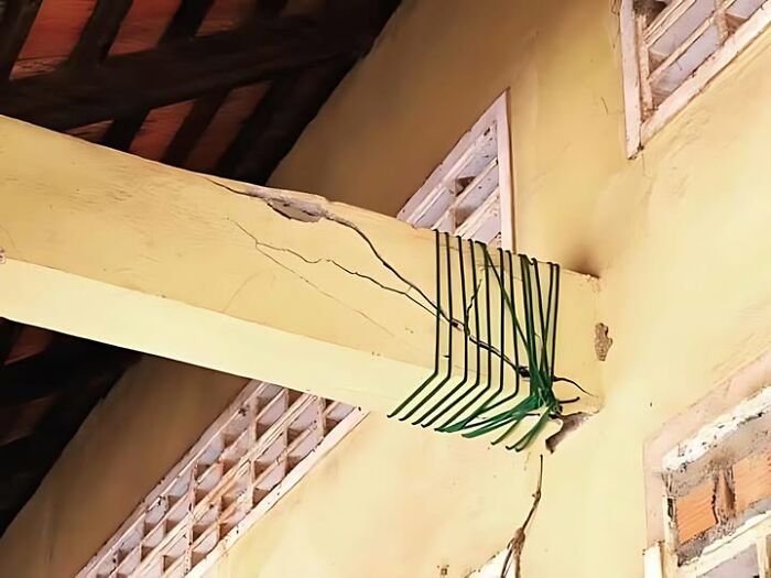 Construction fail: cracked beam haphazardly repaired with green strings in a yellow room.