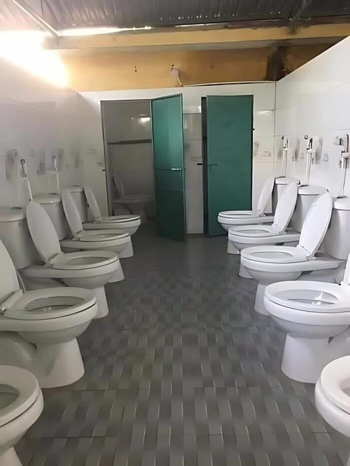 Public restroom with multiple toilets facing each other, showcasing a construction fail.