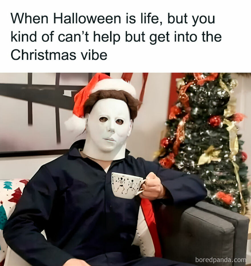 Person in a mask wearing a Santa hat, sipping coffee beside a decorated Christmas tree. Funny Christmas meme.