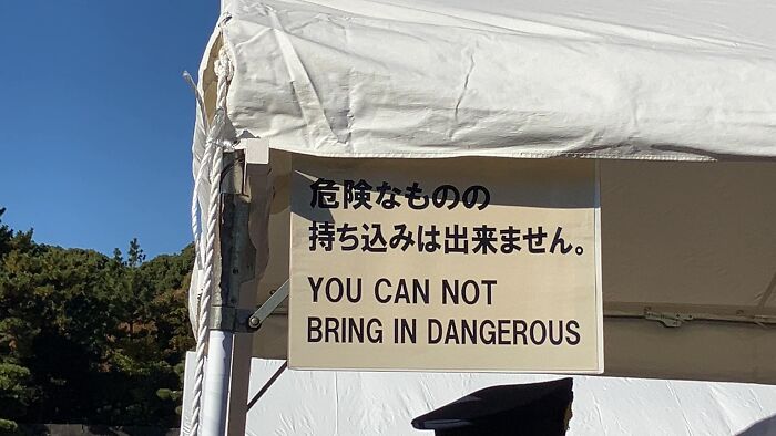 Sign at a Japanese tent with humorous translation: "YOU CAN NOT BRING IN DANGEROUS."