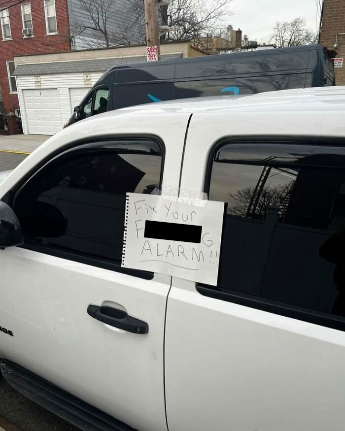 Funny note on a car window in New York, humorously telling the owner to fix their alarm.