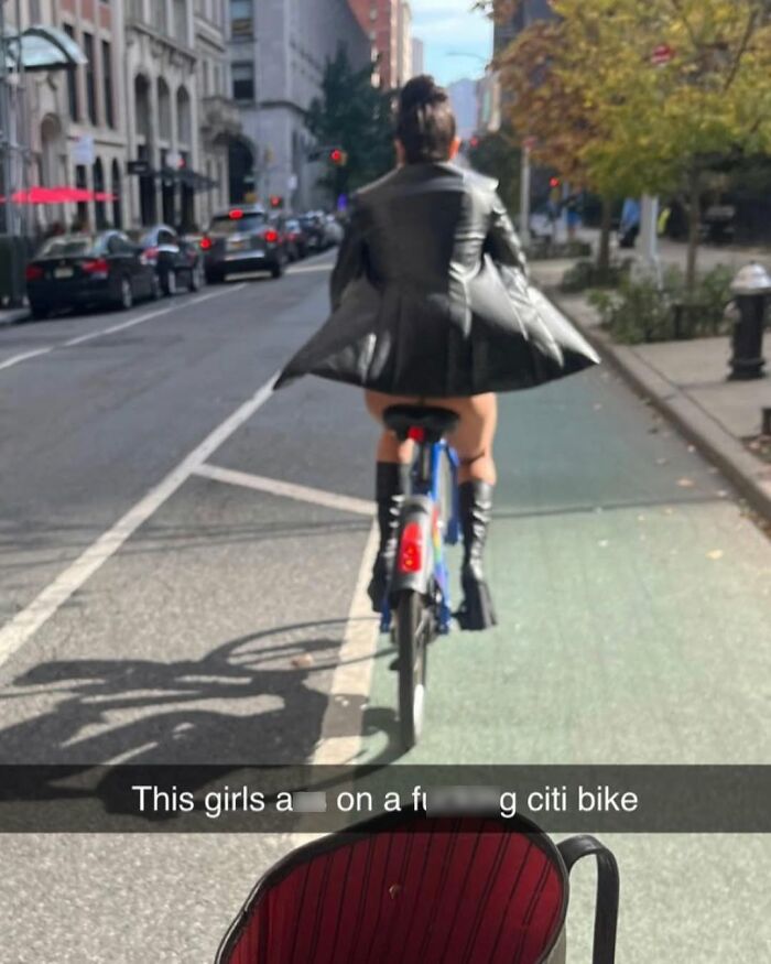 Woman in black jacket riding a Citi Bike in a funny scene, New York street background.