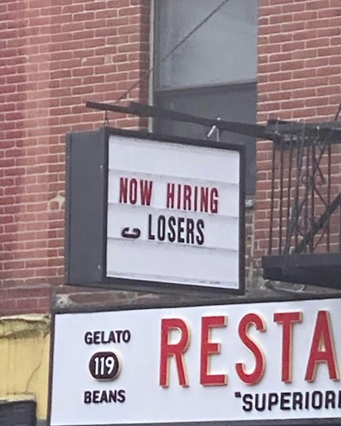 Sign reading "Now Hiring Losers" in New York, showcasing humorous street sign.