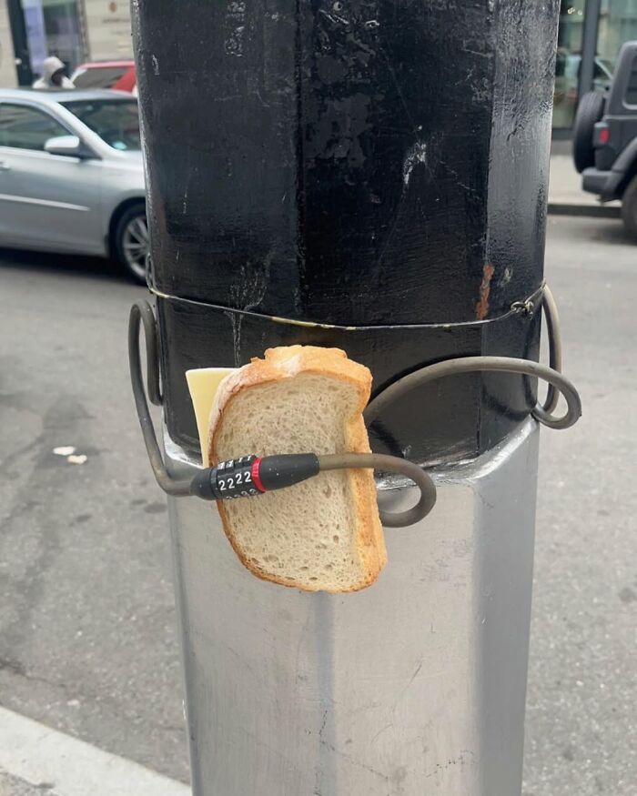 Bread slice locked with a cable on a New York street pole, humorous scene.