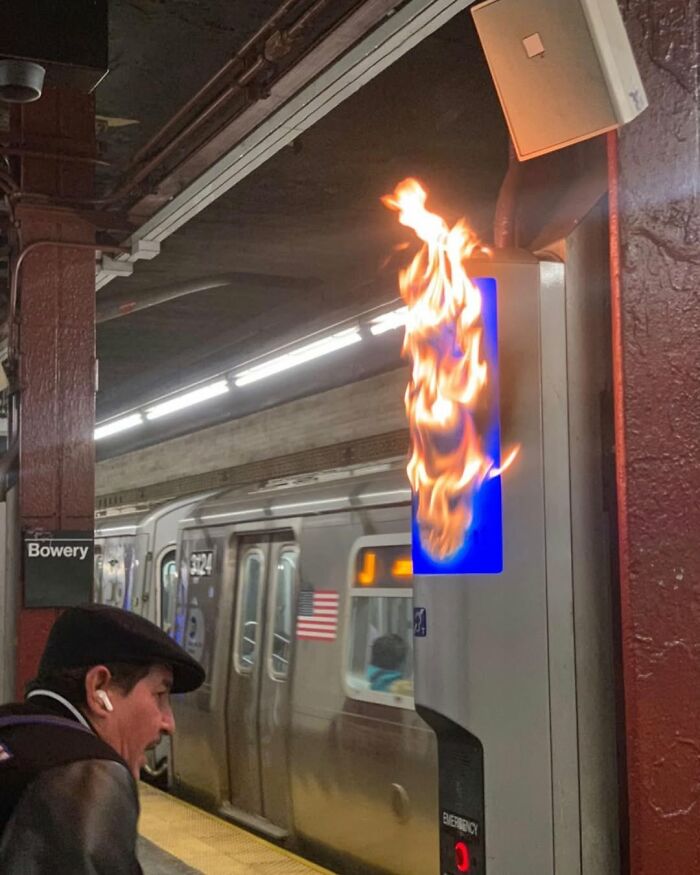 Sign on fire in New York subway station, surprising a passerby.