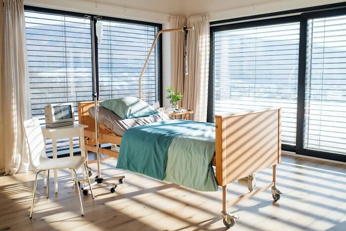 Hospital room with an empty bed, IV stand, and sunlight streaming through the windows, representing survival against all odds.