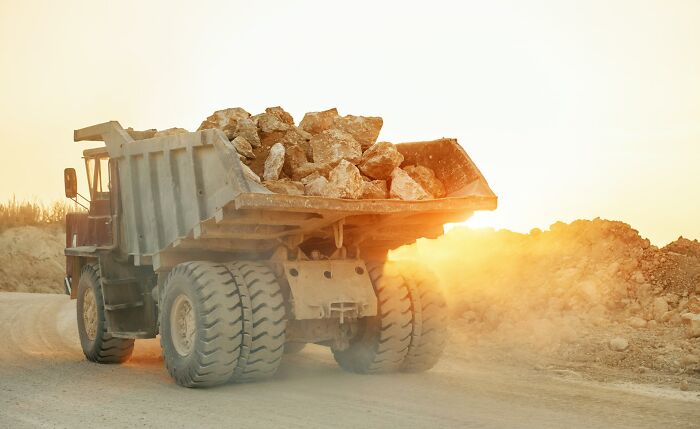 Dump truck on a dusty road at sunset, loaded with rocks, symbolizing moment realized dating idiot concept.