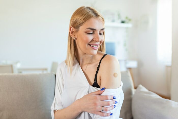 Smiling woman on a couch, showing her shoulder patch, highlighting the difference exercise can make for health.