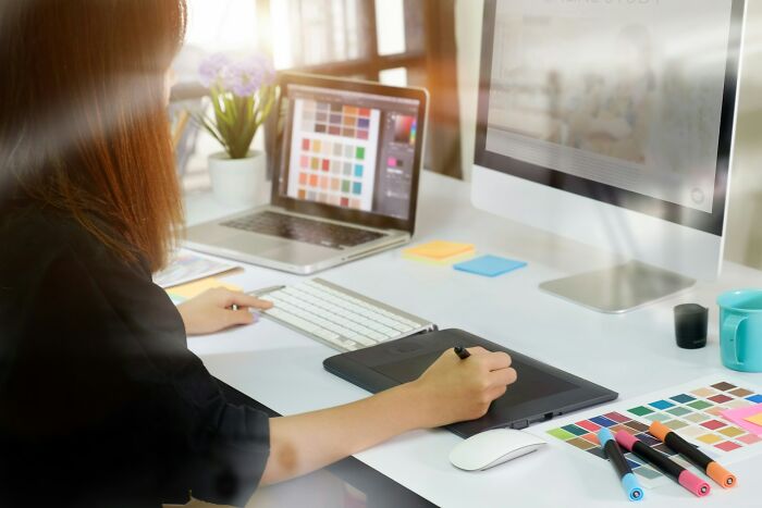 Person working at a computer with a graphics tablet, illustrating a less fun reality of creative jobs.