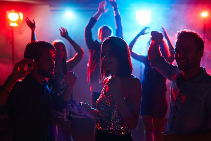 People experiencing an astonishing coincidence while dancing in a vibrant, colorful club atmosphere.