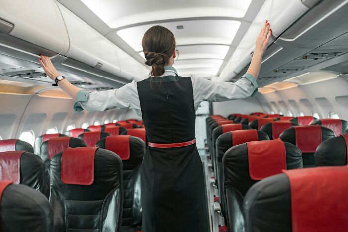 Flight attendant adjusts luggage, illustrating how 'fun' jobs can be less enjoyable than people imagine.