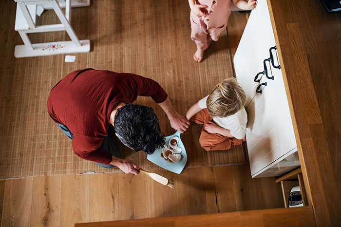 Parent interacting with young child at home, discussing school behavior issues.