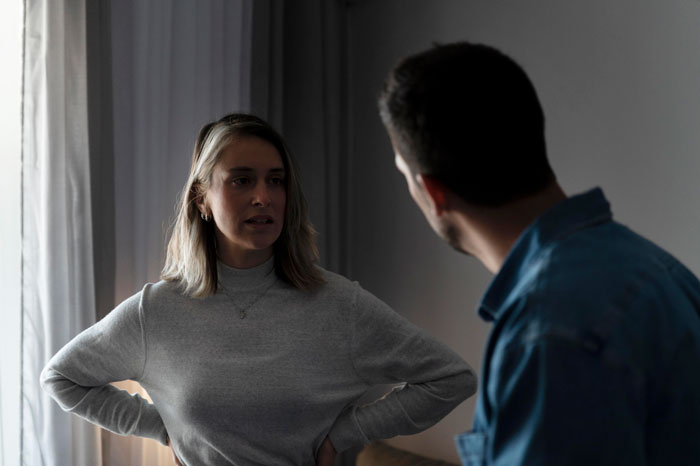 A couple in a dimly lit room engaged in a heated discussion, conveying themes of girlfriend-baby-drama.