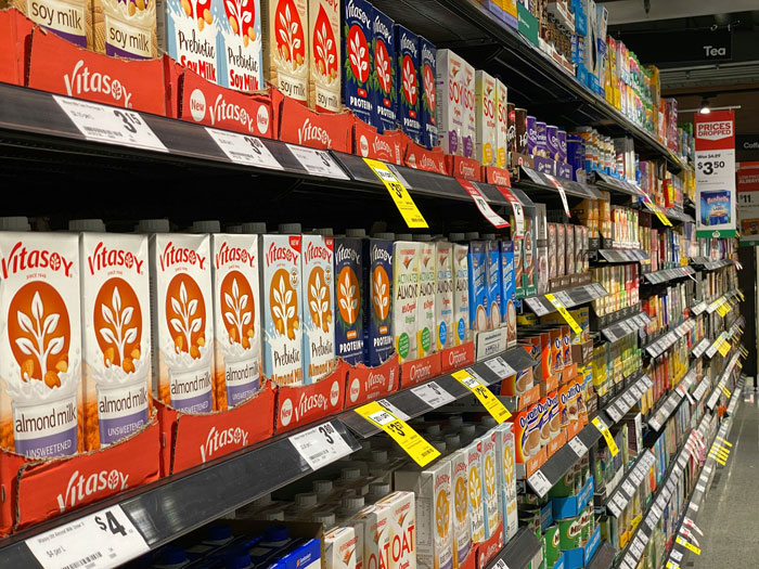 Grocery shelf in Arctic store displays various milk alternatives with high prices, highlighting expensive groceries.