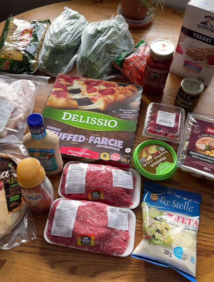 Groceries from the Arctic on a table, showcasing high costs with ground beef, pizza, fresh produce, and packaged foods.